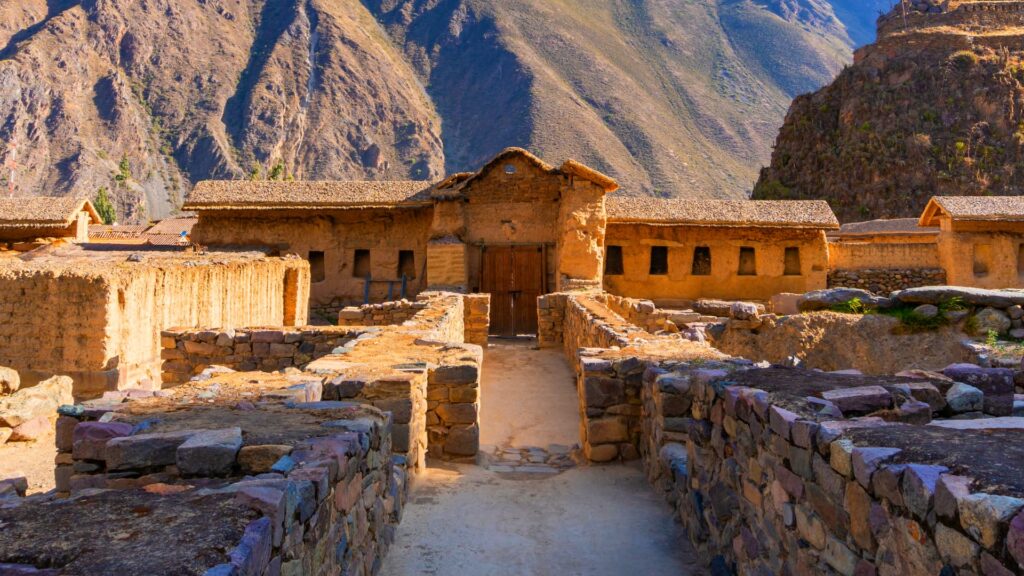 Well-preserved Inca ruins in Ollantaytambo, showcasing ancient stone pathways and adobe buildings against the backdrop of the towering Andean mountains - Machupicchu Andean Wonder.